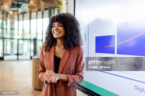 mujer africana sonriente dando presentación en startup - presentador fotografías e imágenes de stock