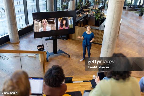 businesswoman discussing with team in office and colleagues on video call - virtual seminar stock pictures, royalty-free photos & images