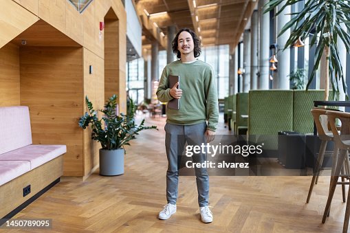 Confident young businessman standing in office lobby Confident young businessman standing in office lobby
