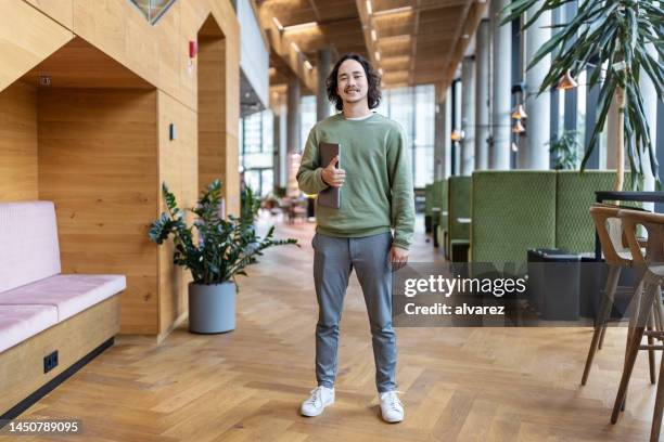 confident young businessman standing in office lobby - fritidskläder bildbanksfoton och bilder