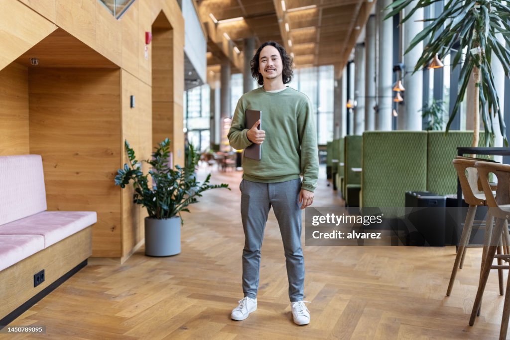Confident young businessman standing in office lobby