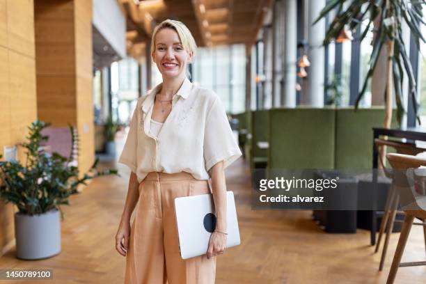 mature businesswoman standing in office lobby - founders stockfoto's en -beelden