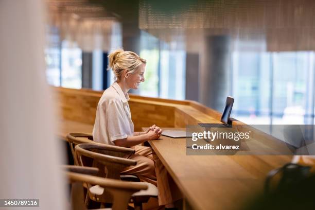 geschäftsfrau auf videoanruf sitzt im coworking-büro - arbeit-im-hybridmodell stock-fotos und bilder