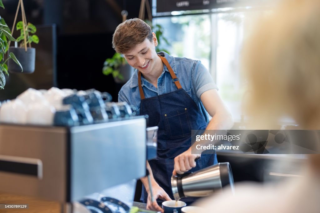 Barista joven sirviendo café al cliente en la cafetería
