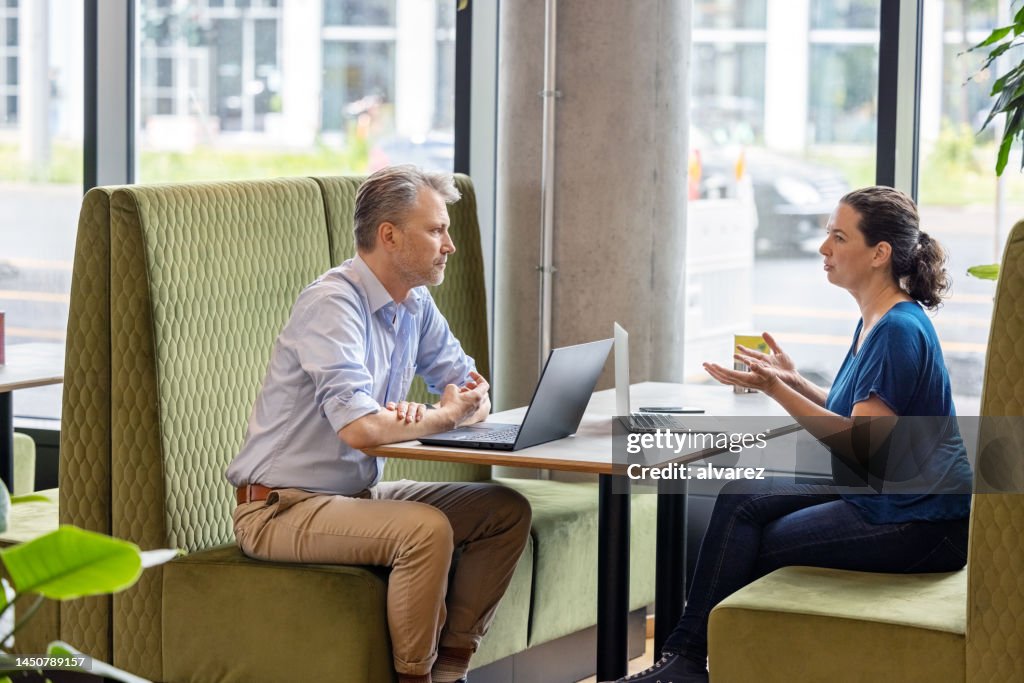 Businesswoman discussing work with a male colleague sitting at cafe