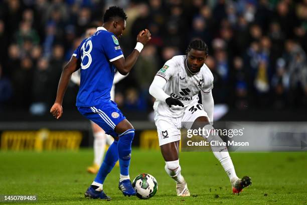 Daniel Amartey of Leicester passes under pressure from Matthew Dennis of MK Dons during the Carabao Cup Fourth Round match between Milton Keynes Dons...