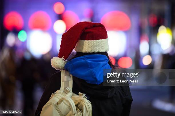 Woman wearing a Santa hat stops to take a photograph of the Christmas lights on December 20, 2022 in London, England. The UK's hospitality sector...