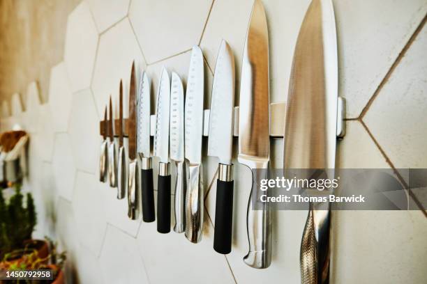 close up shot of kitchen knives on wall in kitchen - kochmesser stock-fotos und bilder