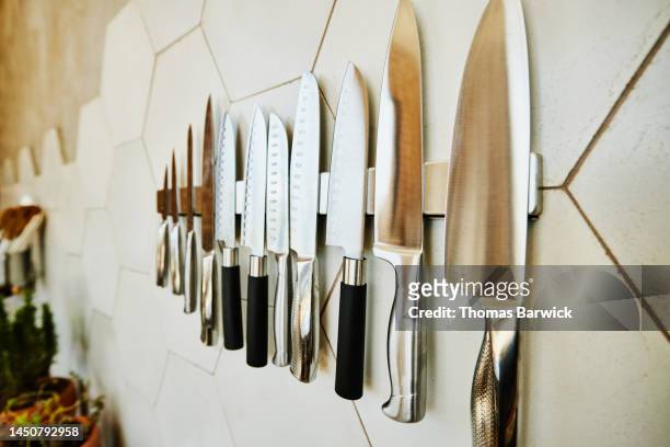 close up shot of kitchen knives on wall in kitchen - keukenmes stockfoto's en -beelden