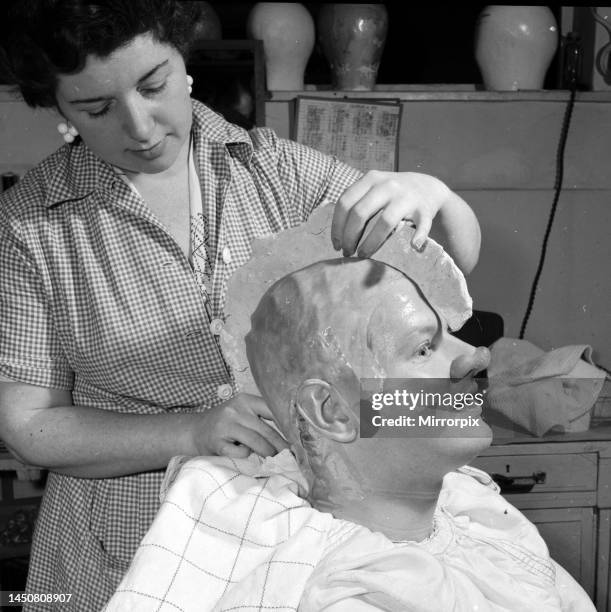 Comedian Benny Hill having a plaster cast of his skull made, so a wig can be correctly fitted. Hill can be seen wearing a false nose made earlier in...