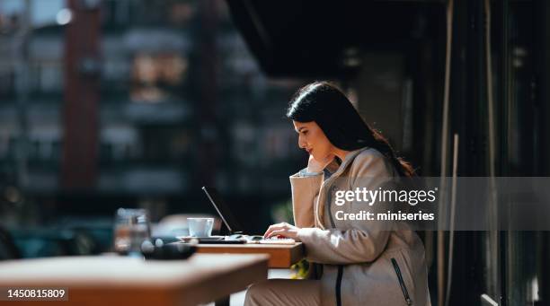 schöne junge geschäftsfrau sitzt am coffeeshop-tisch auf der straße und arbeitet an ihrem tablet - black white business poeple portraits dark stock-fotos und bilder