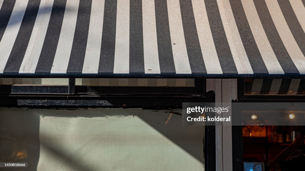 Striped awning of the shop in bright sunlight