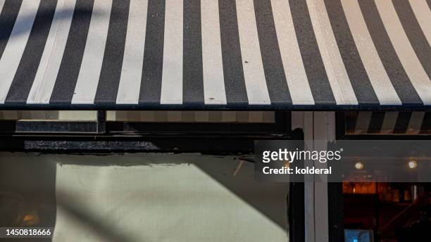 striped awning of the shop in bright sunlight - striped awning stock pictures, royalty-free photos & images