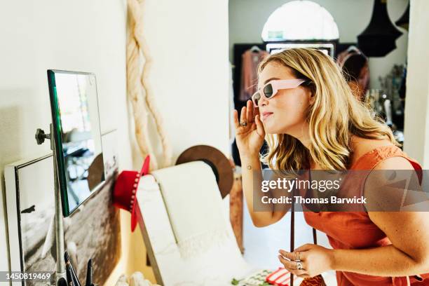 medium shot of woman trying on sunglasses while shopping during vacation - trying on stock pictures, royalty-free photos & images