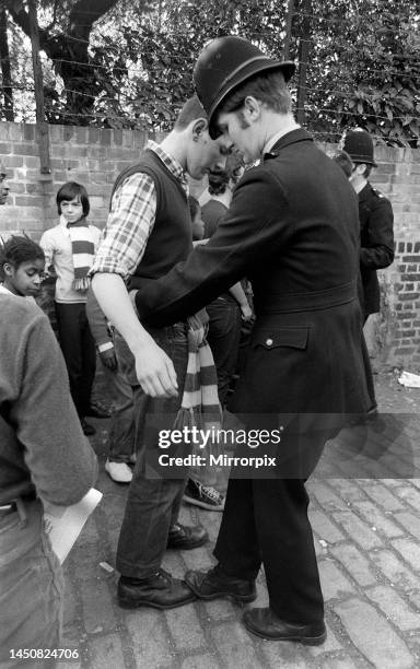 Chelsea fans are frisked and their boots checked for steel toe caps by a police officer before the Chelsea versus Arsenal league game at Stamford...