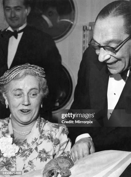 Man showing off a chicken drumstick to a woman at a dinner partycirca 1955.