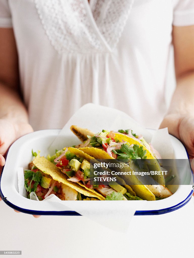 Woman holding bowl of fish tacos