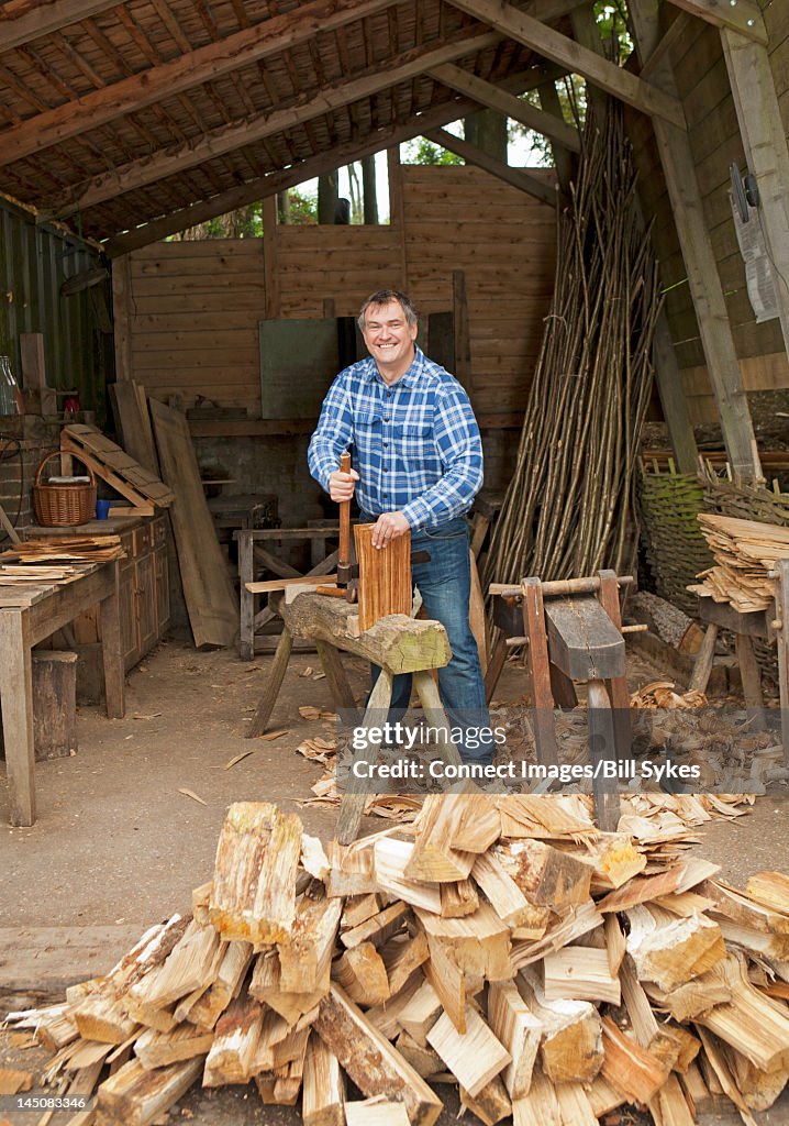 Older man chopping wood in shop