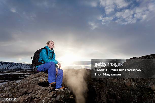 hiker sitting on rock formation in snow - winter and sun stockfoto's en -beelden