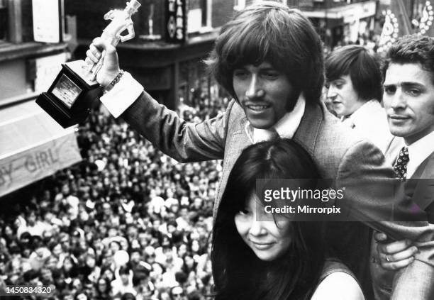 Barry Gibb of the Bee Gees holding the John Stephen statuette presented to him by Miss Tsai Chinn after he was voted 'Best Dressed Personality Of The...