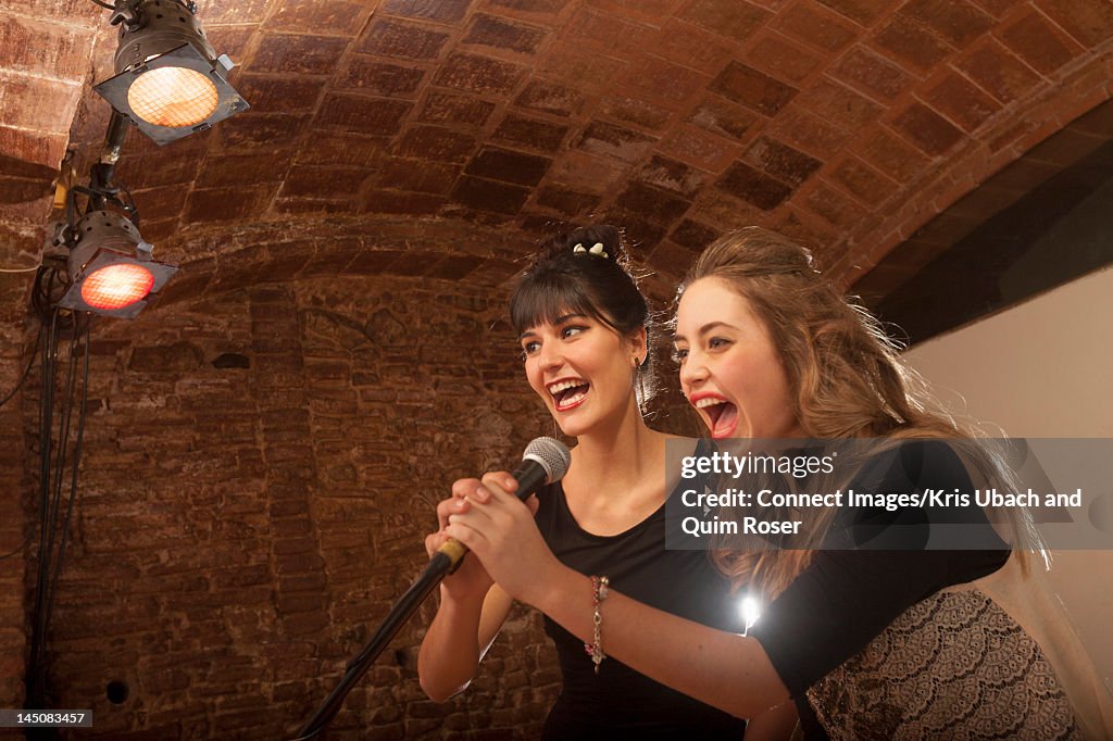 Women singing together in microphone