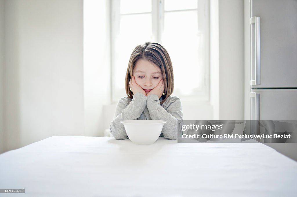 Girl examining empty bowl at table