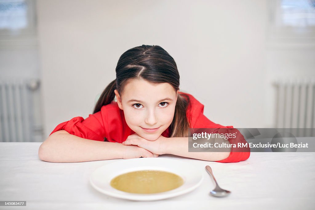 Girl sitting at table with bowl of soup