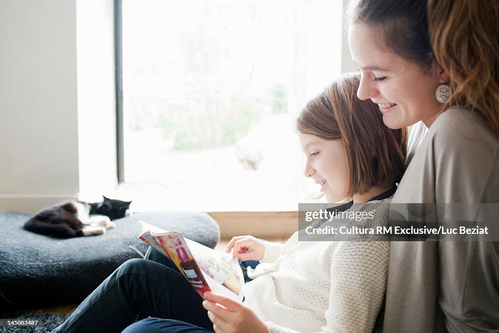 Sisters reading together on sofa