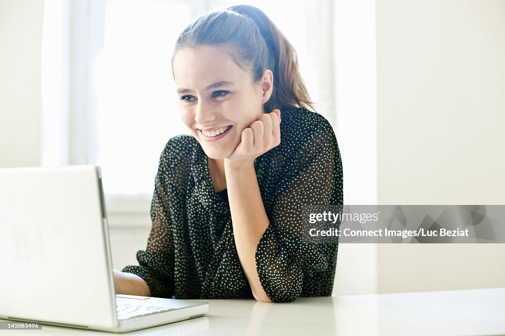 Smiling teenage girl using laptop