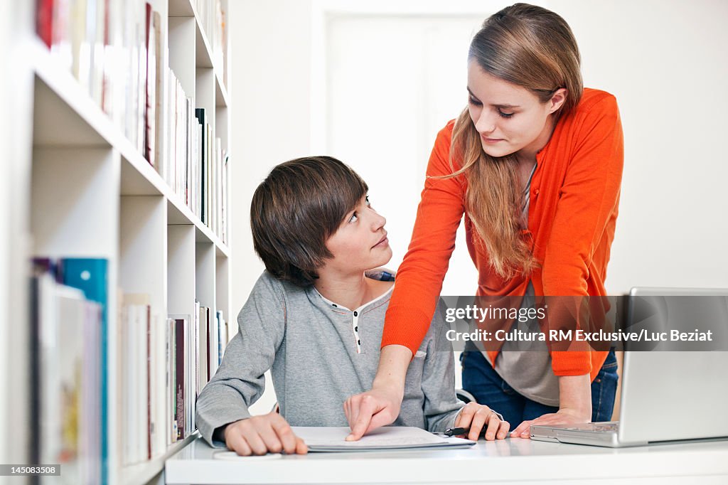 Girl helping friend study in library