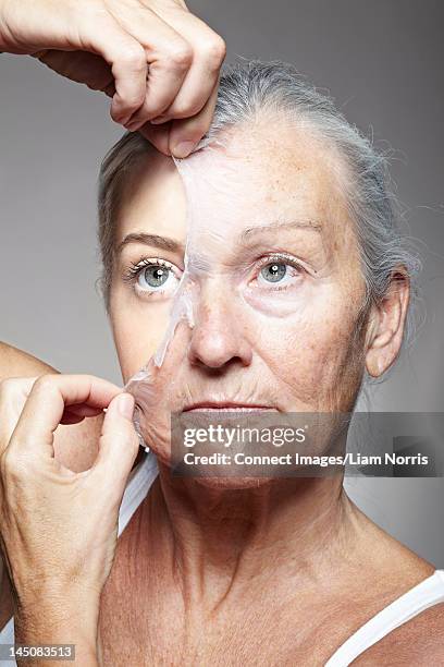 young woman peeling off old mask - peel off mask stock-fotos und bilder