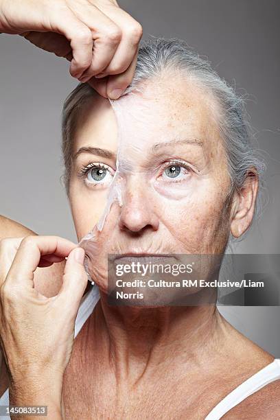 young woman peeling off old mask - aging skin stock pictures, royalty-free photos & images