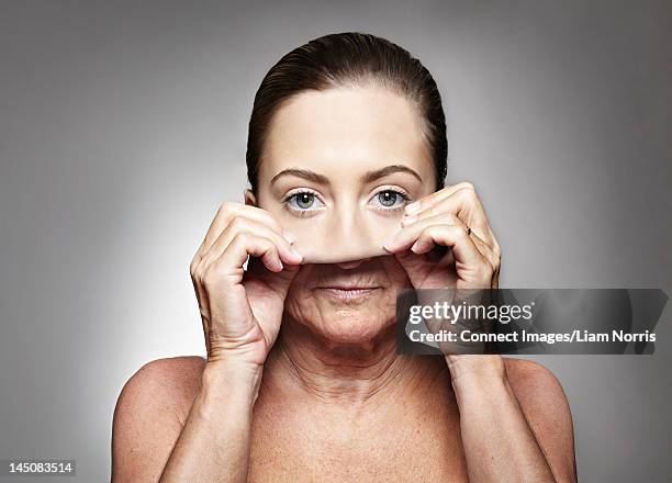 older woman pulling on young mask - removing mask stock pictures, royalty-free photos & images