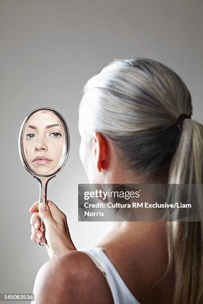 woman seeing herself younger in mirror - vanity stock pictures, royalty-free photos & images