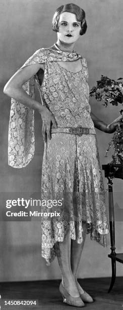 Model wearing a long patterned dress showing the popular uneven hemline in 1929.