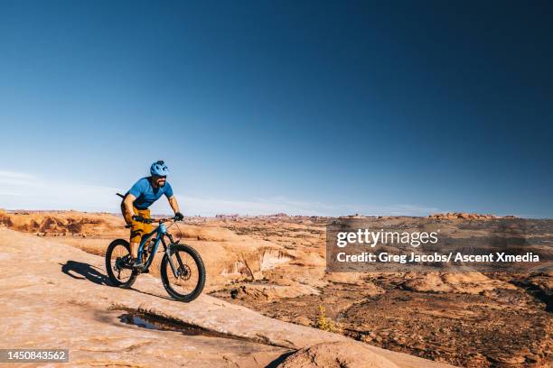 mountain biker follows trail through arid desert - grand county utah stock pictures, royalty-free photos & images