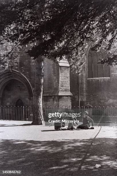 Childhood confidences in the playground of the girls school beside the walls of Tewesbury Abbey in Gloucestershire/Sitting in shade of treecirca 1935.