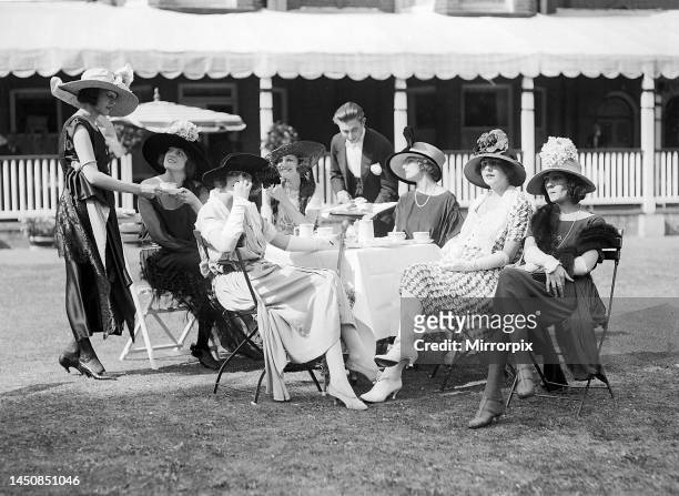 Racegoers sit in a group at a table watching the events of the day at Ascot. June 1921.