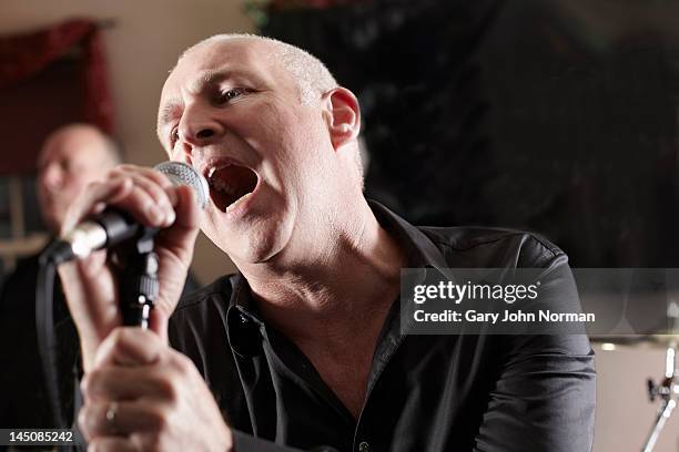 mature male lead singer singing into microphone - cantante principal cantante fotografías e imágenes de stock