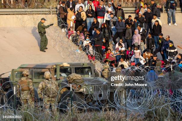 Border Patrol agent speaks to immigrants blocked from entering a high-traffic illegal border crossing area along Rio Grande in El Paso, Texas on...