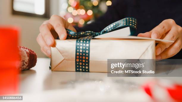 closeup of woman hands writing greeting card with christmas gift boxes on table at home. - holiday message stock pictures, royalty-free photos & images