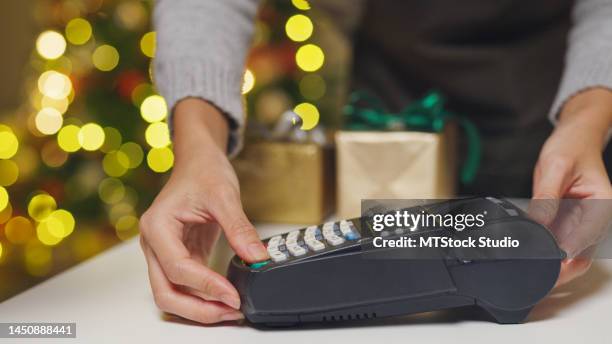 closeup hand of asian woman purchase by credit card on electronic payment machine or card reader in small shop at christmas night. - machine christmas tree stock pictures, royalty-free photos & images