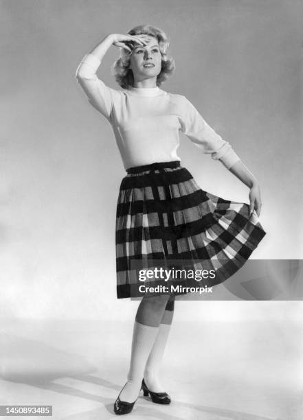 Model Rita Rayee wearing as long sleeved top and patterned knee length skirt with shoes and stockings. September 1960.