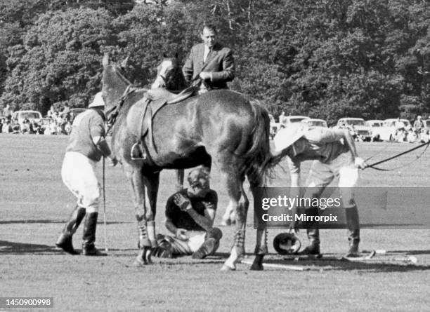Prince Philip crouches beneath his horse Lightning after he collided with three others during a game at Windsor Great Park. He lay still for a few...