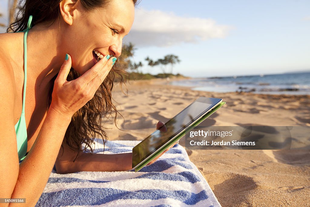 Female using a digital tablet at the beach.