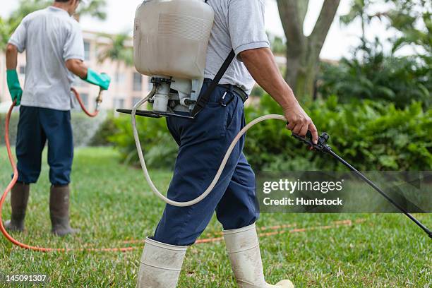 two pest control technicians with portable spray rigs using spray guns - herbicide stock pictures, royalty-free photos & images