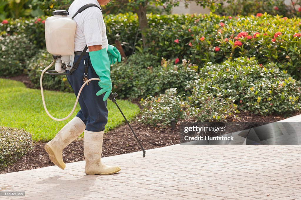 Pest control technician using portable spray rig