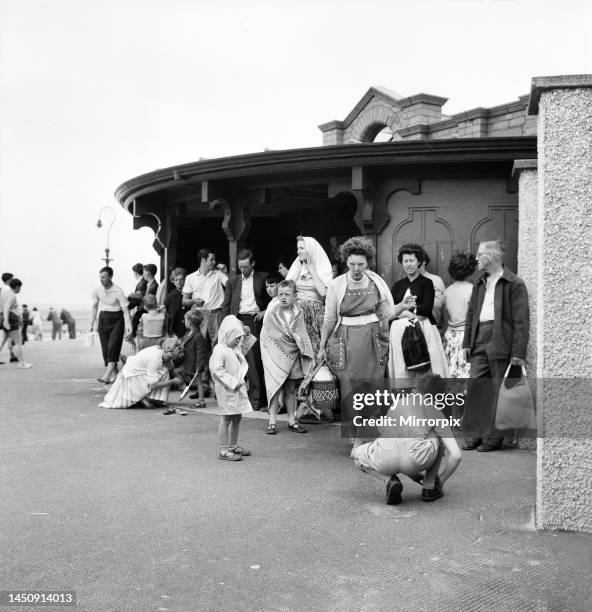 Holidaymakers shelter from the wind on the seafront at Devon. 5th June 1960.