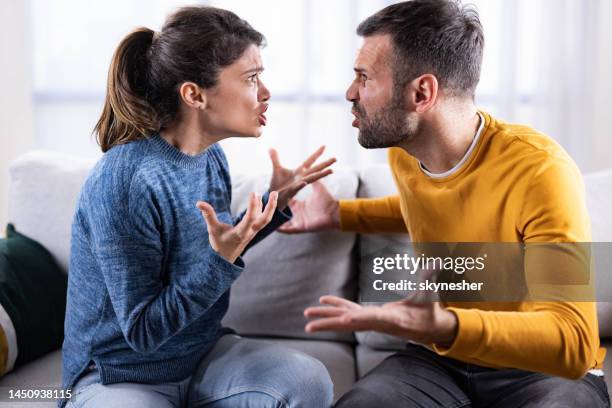 media pareja adulta discutiendo en el sofá en casa. - discusión fotografías e imágenes de stock