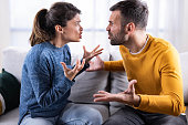 Mid adult couple arguing on sofa at home.